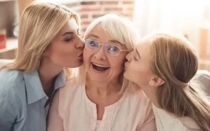A grandmother is kissed by her daughter and her granddaughter